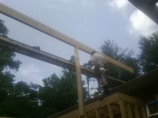 Carpenter setting a ridge beam over a new addition frame — Ice Dam Removal by Roofing Brothers in Shortsville