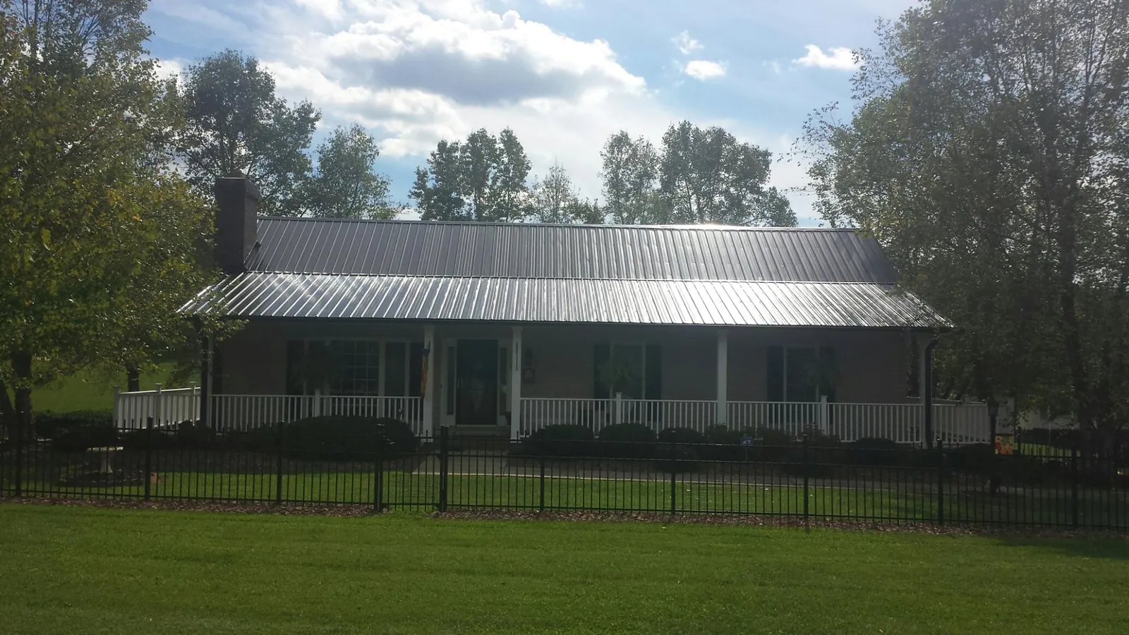 Gray metal roof on a brick ranch with a full width front porch — Gutter Guard Installation work by our crew in Shortsville