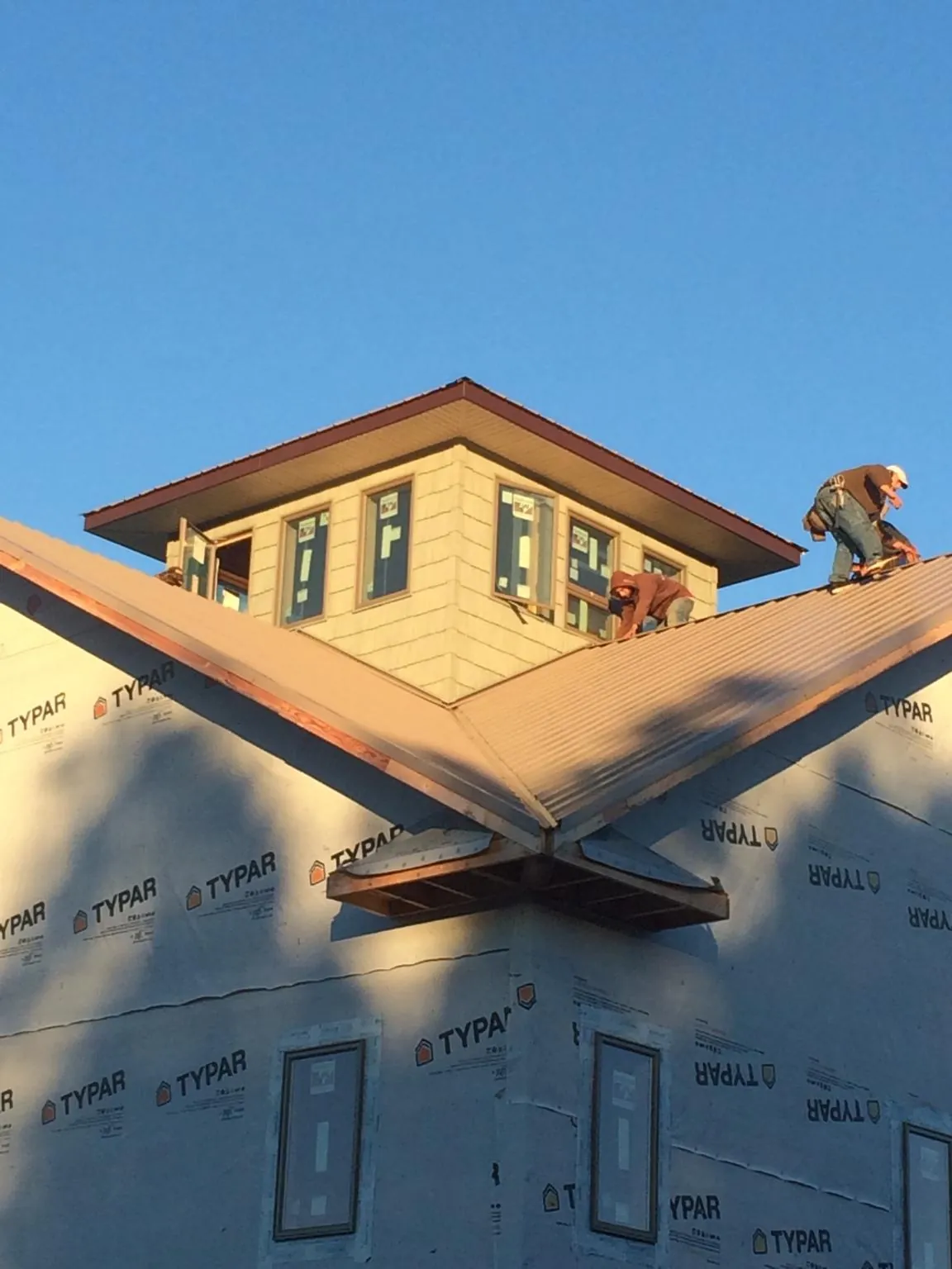 Roofers working around a rooftop cupola on a new metal roof at sunset — Roof Waterproofing in Shortsville by Roofing Brothers